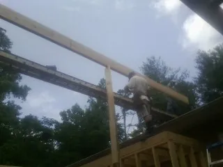 Carpenter setting a ridge beam over a new addition frame — Ice Dam Removal by Roofing Brothers in Thomasboro