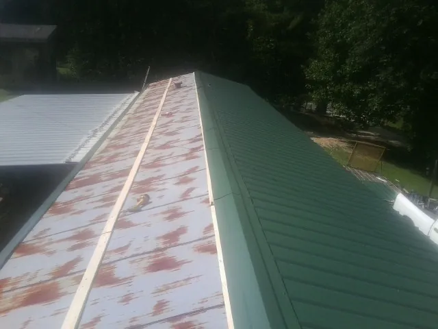 Old rusted panels beside newly installed green metal roofing — Wind Damage Roof Repair by Roofing Brothers in Thomasboro