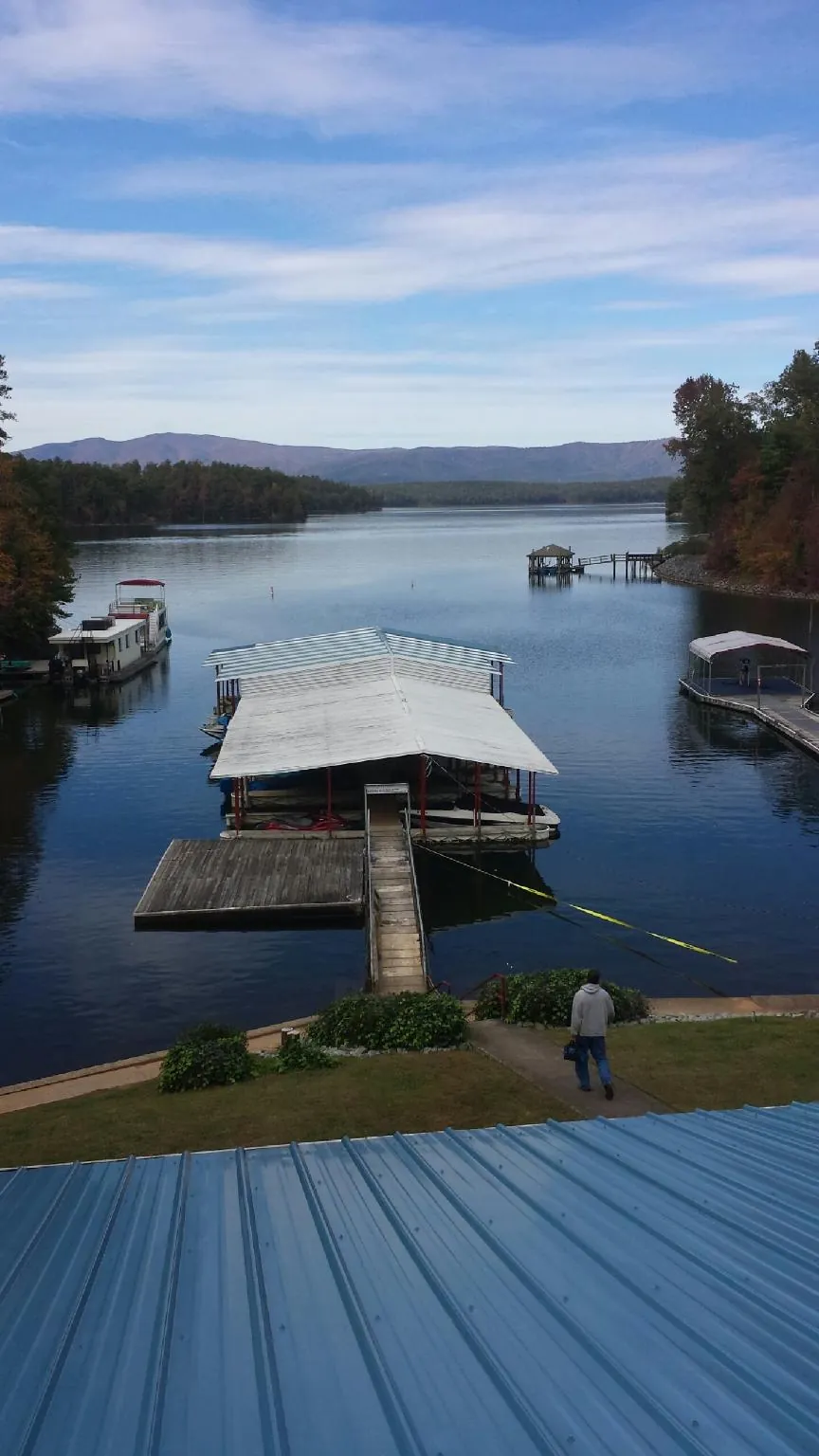 View across a lake from a newly installed blue metal roof in Thomasboro