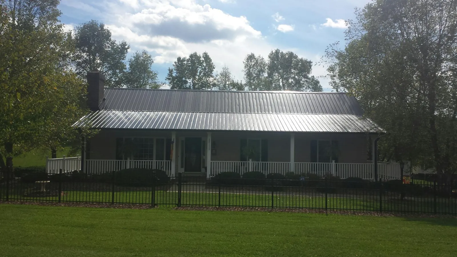 Gray metal roof on a brick ranch with a full width front porch — Gutter Guard Installation work by our crew in Thomasboro