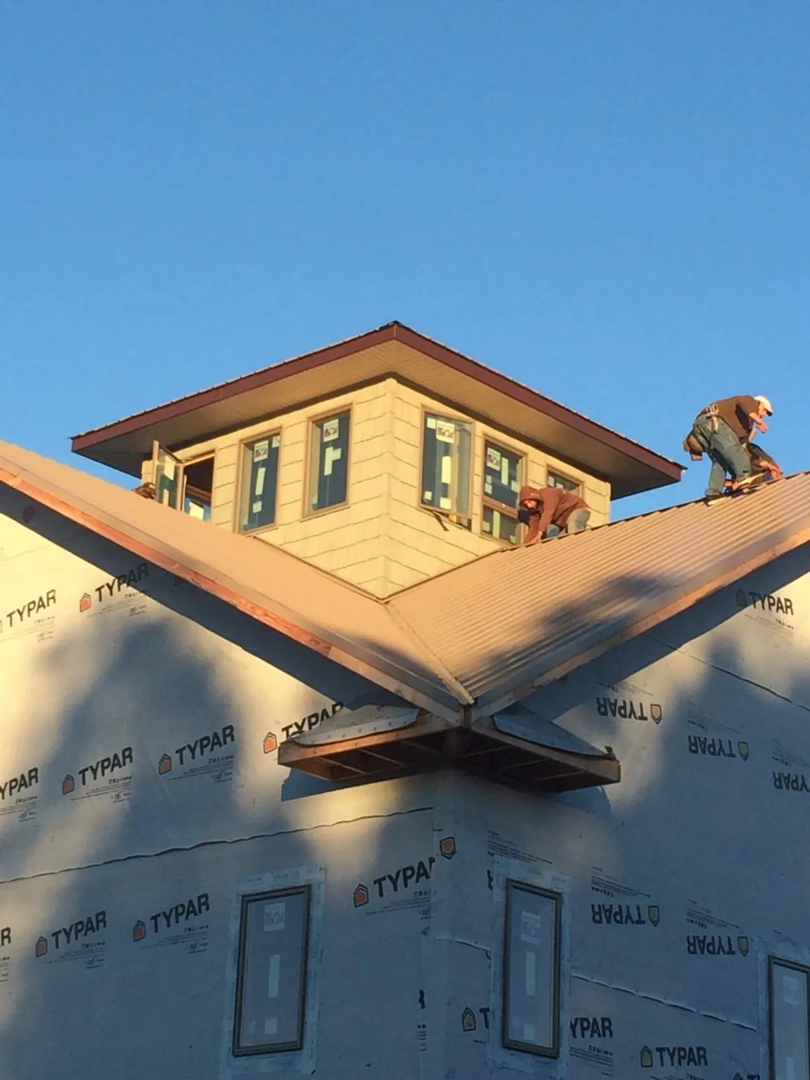 Roofers working around a rooftop cupola on a new metal roof at sunset — Roof Waterproofing in Thomasboro by Roofing Brothers